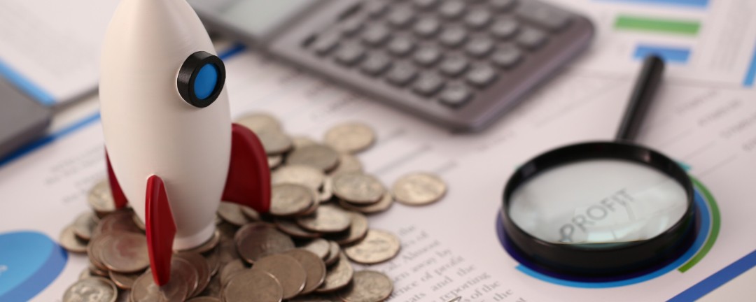 Rakete auf Schreibtisch zwischen Geld und Tastatur