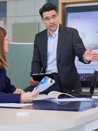 Der KfW-Chefvolkswirt spricht mit zwei Kollegen am Tisch.