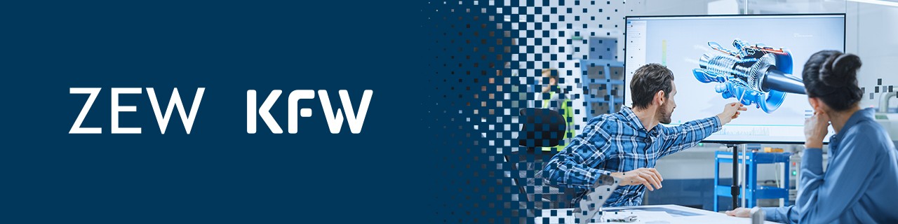 Zwei Mitarbeitende sitzen vor 4 Bildschirmen