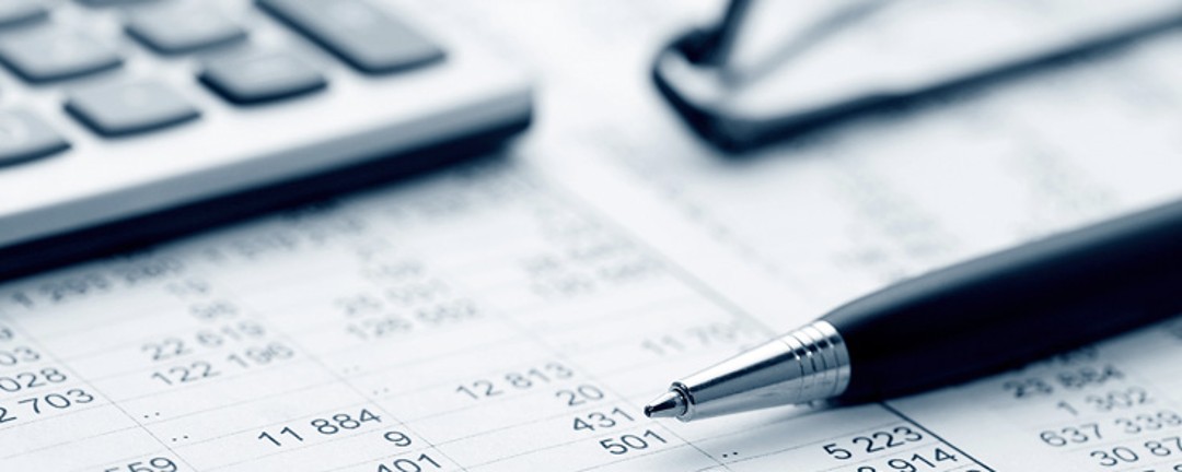 Ein Taschenrechner, ein Stift und ein Papier mit Zahlen liegen auf dem Tisch