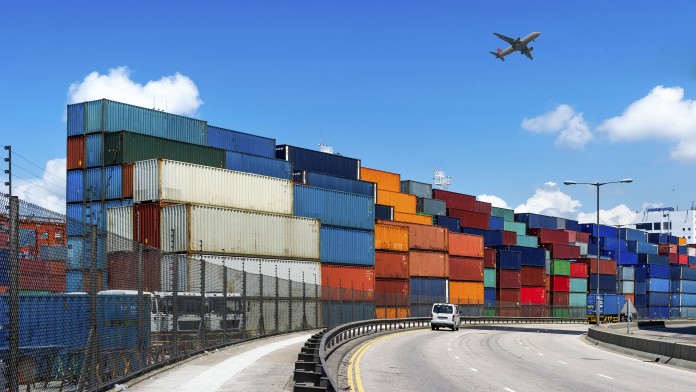 Container im Hafen, Flugzeug im Hintergrund und Straße im Vordergrund