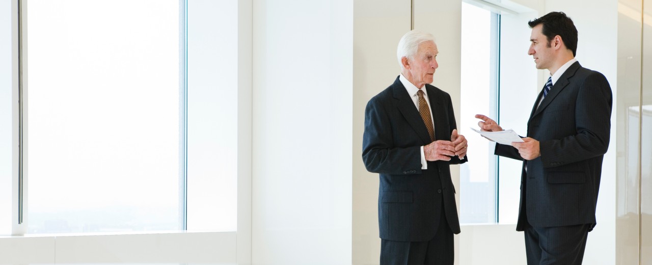 Ein älterer Unternehmensinhaber im Gespräch mit einem jungen Mitarbeiter