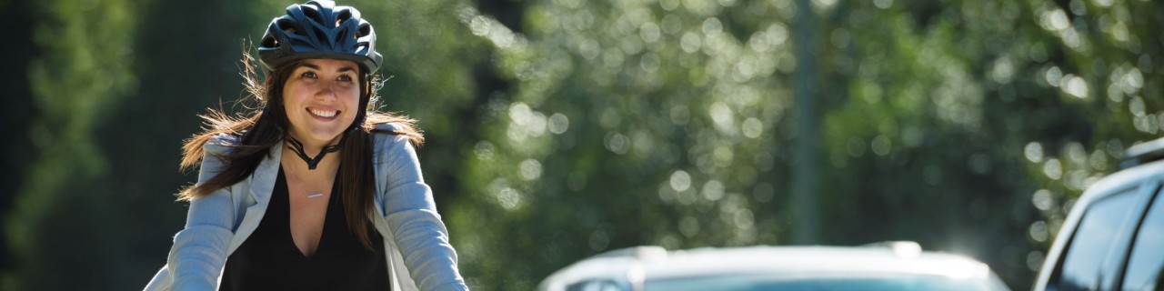 Eine Frau fährt Fahrrad auf einer mit Autos befahrenen Straße