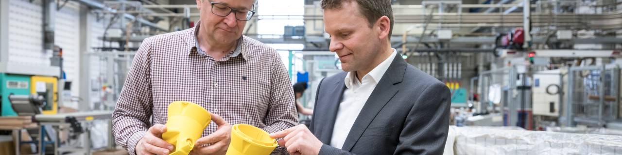 Chef überprüft mit Mitarbeiter ein produziertes Bauteil
