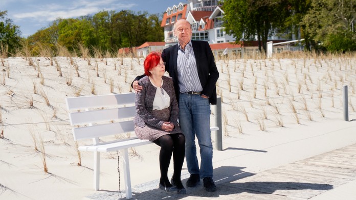 Ehepaar am Strand vor Hotel