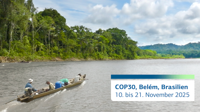 Drei Männer in einem kleinen Kanu auf einem Fluss neben dem Regenwald.