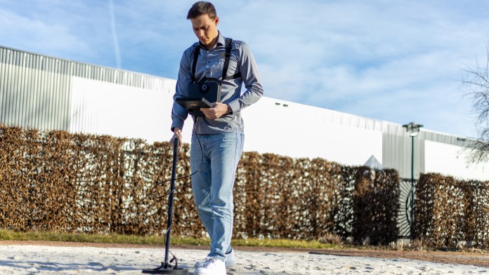 EIn OKM-Mitarbeiter arbeitet mit einem Metalldetektor