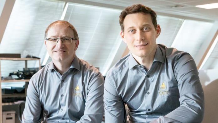 Zwei Männer, Stephan Grund und Christian Becker von OKM, sitzen in einer Halle 
