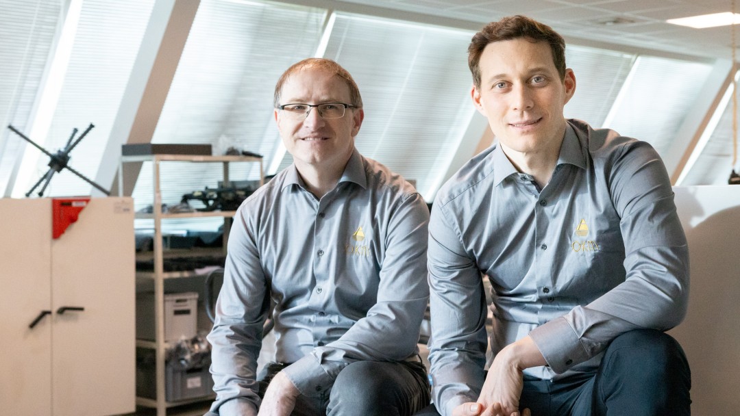 Zwei Männer, Stephan Grund und Christian Becker von OKM, sitzen in einer Halle 
