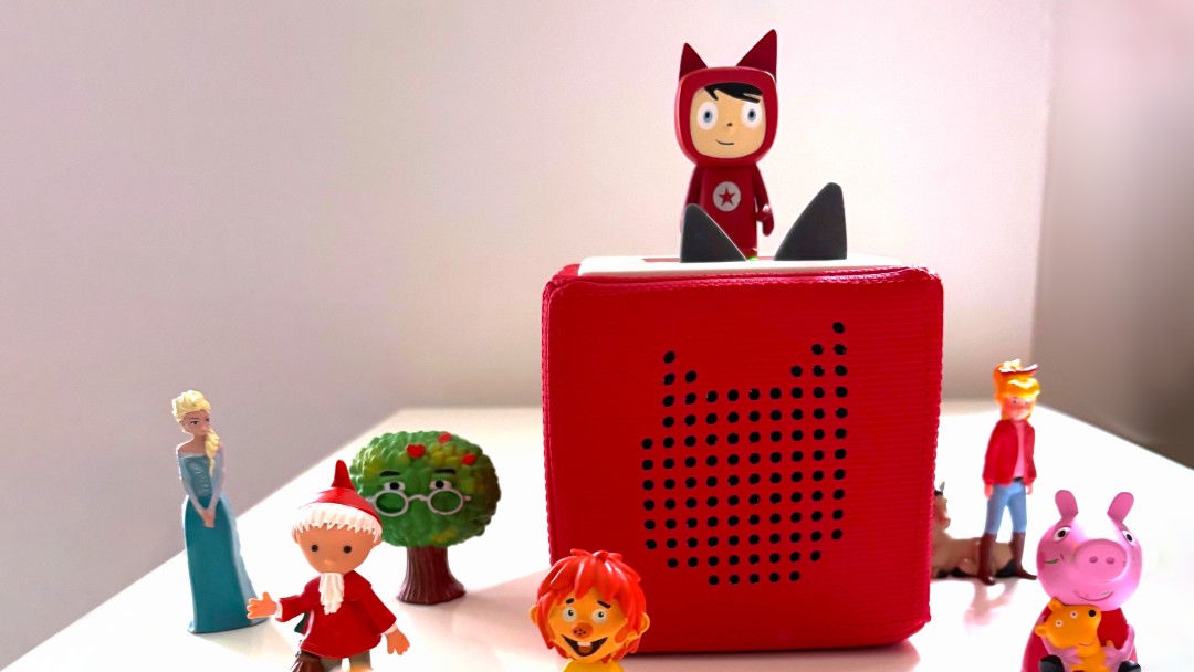 Eine Toniebox und mehrere Tonie-Figuren stehen auf einem Tisch