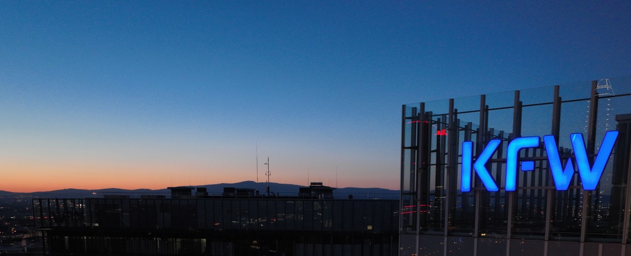 Logo der KfW am Haupthaus im Abendhimmel