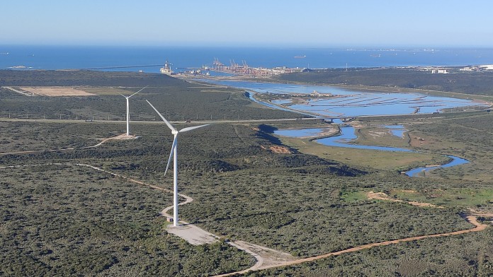 landscape with a hydrogen terminal harbour and wind turbines in the foreground 