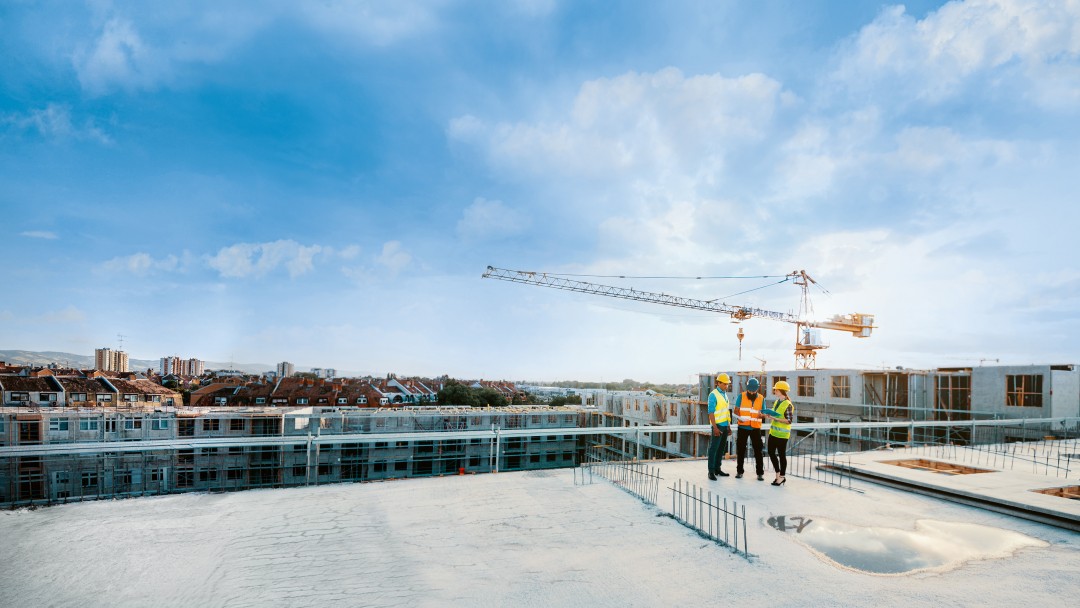 Mitarbeiter auf einer Baustelle, die Schutzausrüstung tragen und die nächste Bauphase besprechen – auf dem Bild sind Figuren in voller Größe zu sehen