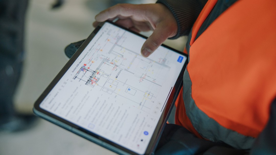 Mitarbeiter mit Tablet, auf dem ein Bauplan zu sehen ist.