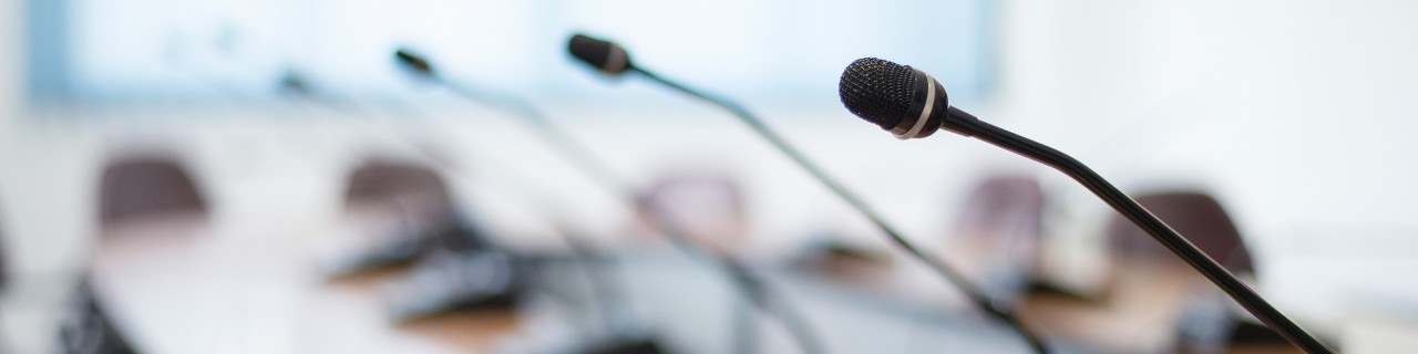A row of table microphones on a long conference table