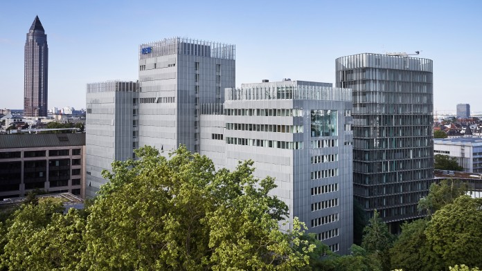 Drohnenaufname des KfW Gebäudes in Frankfurt. Im Vordergrund Baumkronen aus dem Palmengarten, mittig das KfW Haupthaus und die IPEX, links im Hintergrund der Messeturm.
