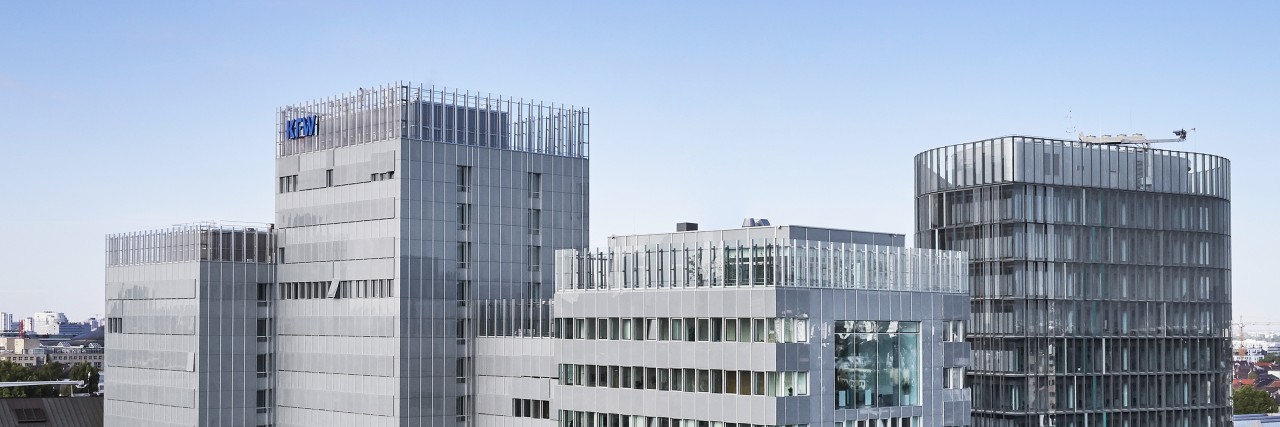 Drohnenaufname des KfW Gebäudes in Frankfurt. Im Vordergrund Baumkronen aus dem Palmengarten, mittig das KfW Haupthaus und die IPEX, links im Hintergrund der Messeturm.