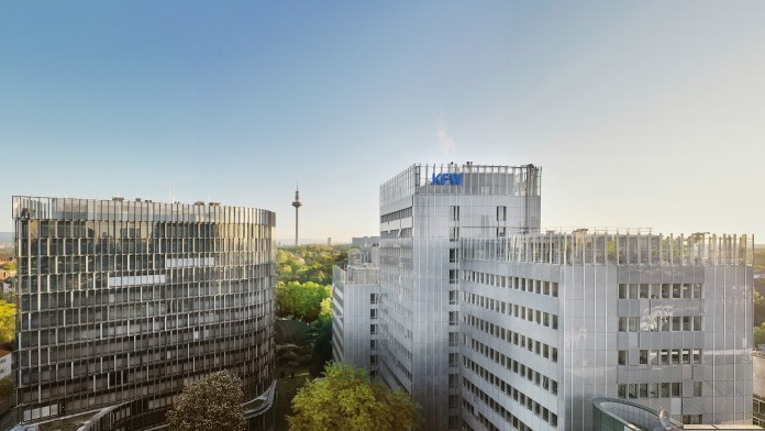 Drohnenaufnahme des KfW Standorts in Frankfurt. Im Vordergrund das Dach der Nordarkade, mittig im Bild das Gebäude der IPEX und das KfW Haupthaus. Der Himmel darüber ist wolkenlos.