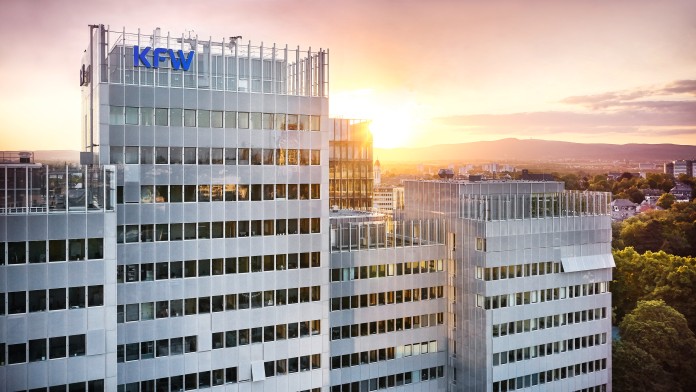 Luftaufnahme des KfW Haupthauses in Frankfurt mit KfW Logo, im Hintergrund ein Sonnenuntergang.