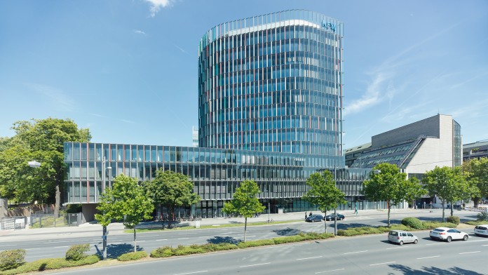 Blick auf das KfW IPEX-Gebäude in Frankfurt an der begrünten Hauptstraße. 