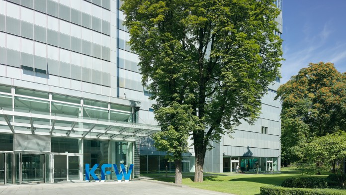 Ausschnitt des Eingangs zum KfW-Haupthaus. Angrenzend wächst ein großer Baum. 