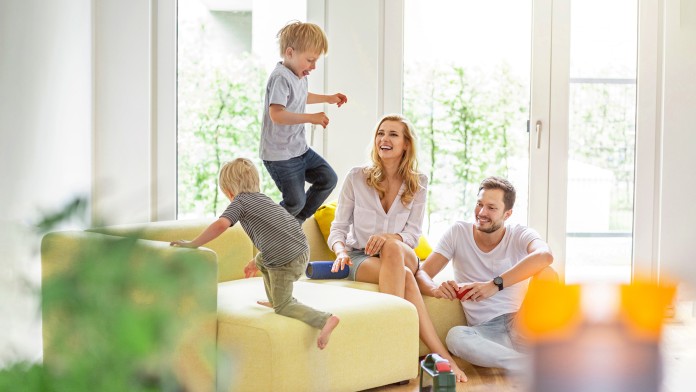 Glückliche Familie im Wohnzimmer ihres neuen Hauses mit herumtollenden Jungen