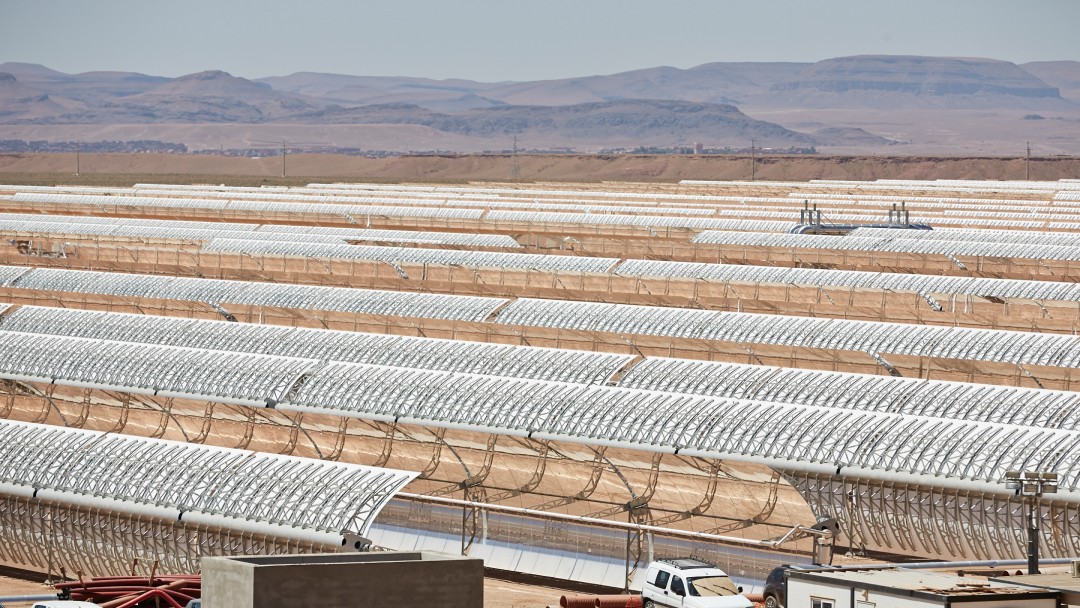 view of some solar panels in a solar thermal system, in the foreground two cars can be seen
