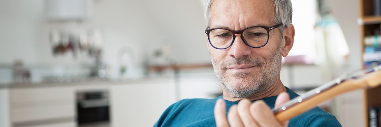 Ein Mann sitzt auf der Couch und spielt Gitarre