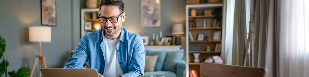 Mann sitzt lächelnd am Laptop