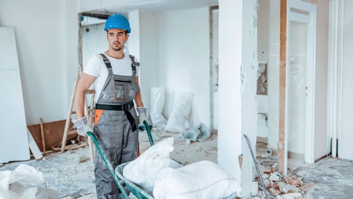 Handwerker mit einer Schubkarre, welcher Sanierungsarbeiten verrichtet 