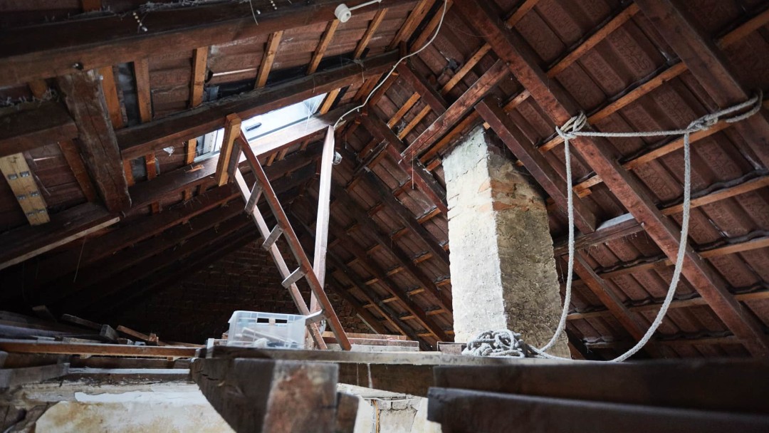 Unter dem Dach eines Hauses vor der Sanierung, die Dachbalken sind zu sehen