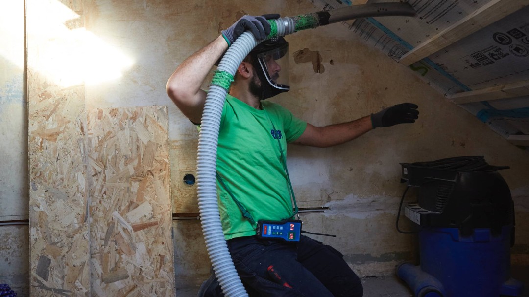 Eine Person dämmt das Dach von innen und nutzt dazu eine spezielle Einblasdämmung