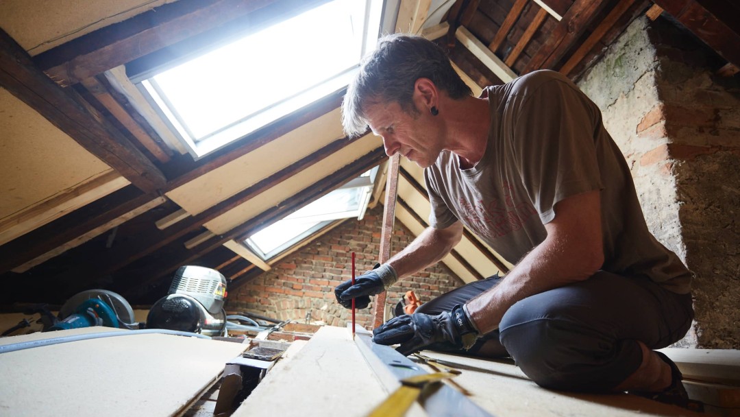Eine Person beim Dachausbau, bei der Innendämmung des Hausdaches