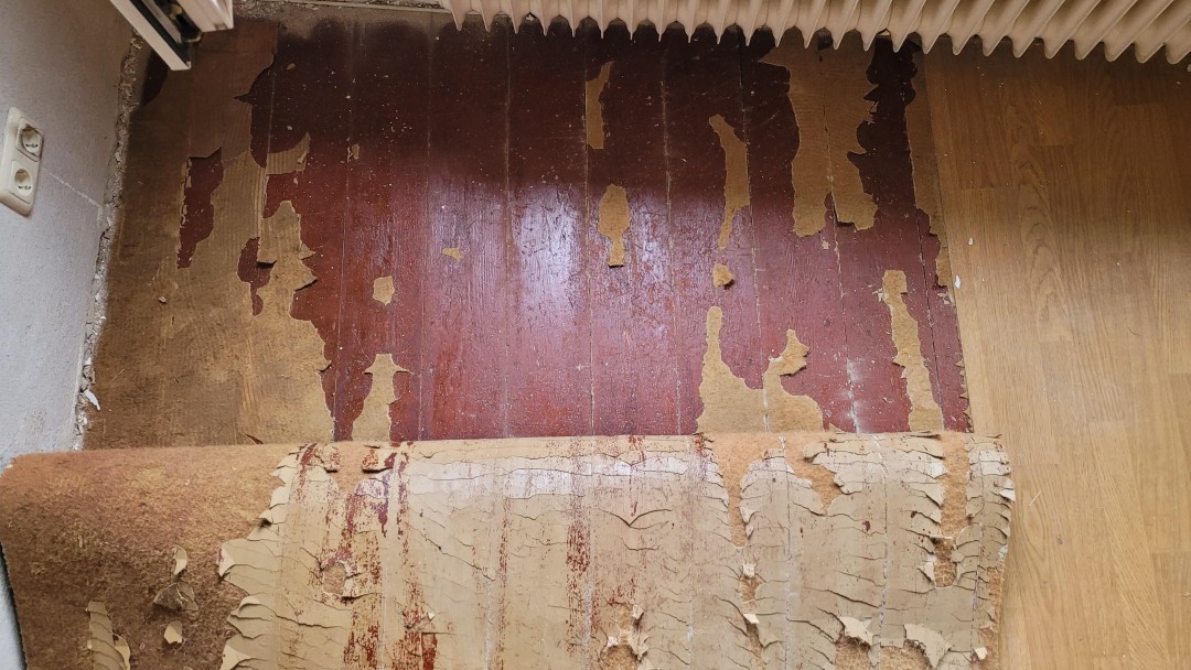 Draufsicht auf einen Fußboden mit einem Vinylbelag, der gerade entfernt wird