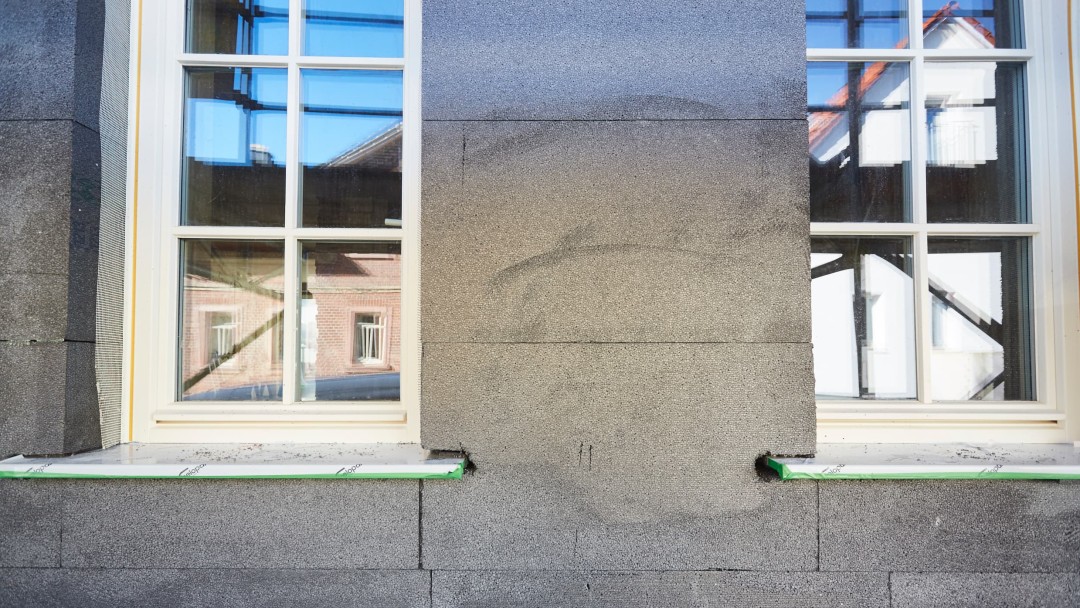 Ansicht einer Fassade, die fertig gedämmt, aber noch nicht verputzt ist