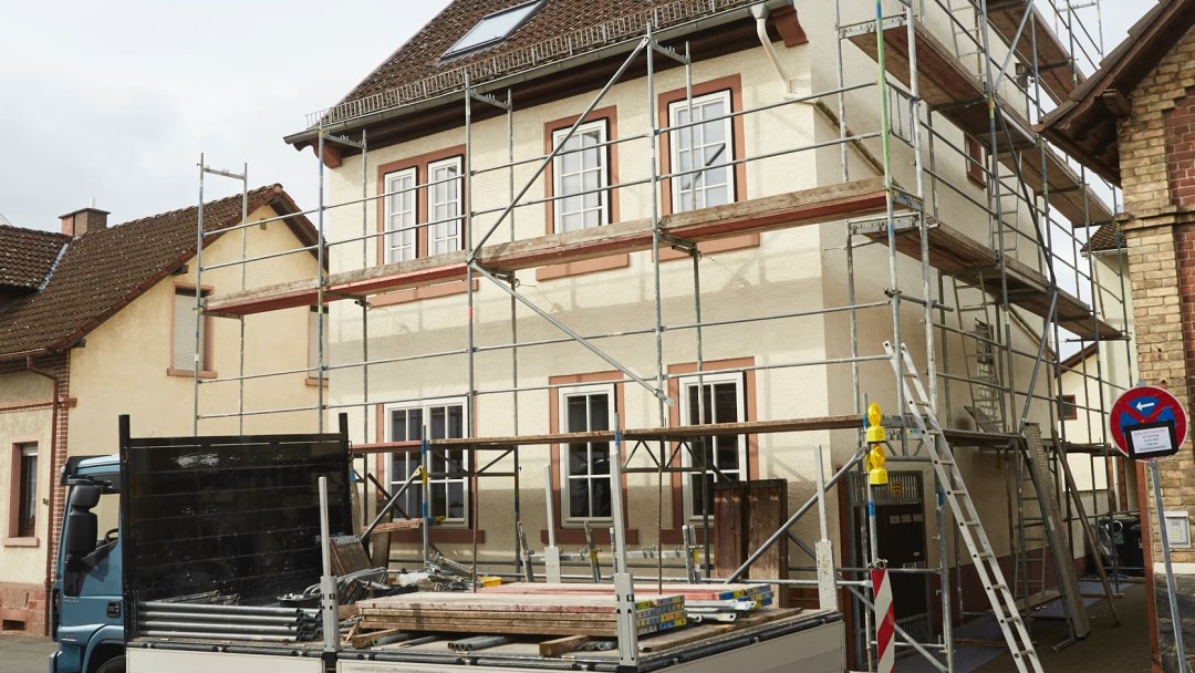 Ein freistehendes Haus ist mit einem Gerüst umstellt, um saniert zu werden