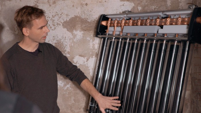 Fachunternehmer betrachtet Solarwärmeanlage im Keller