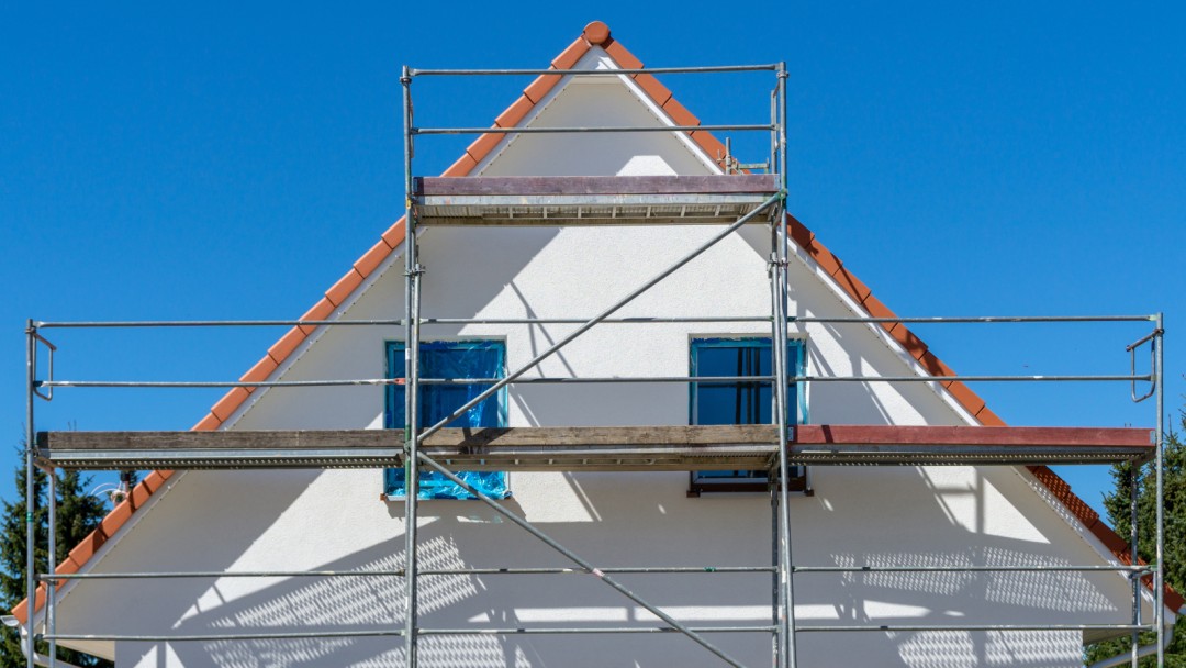 weiße Fassade eines neuen Einfamilienhauses mit Gerüst an der Fassade