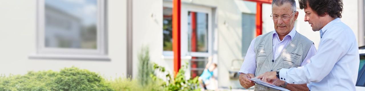Energieeffizienz-Experte erklärt einem Mann vor dem Haus energetische Maßnahmen 