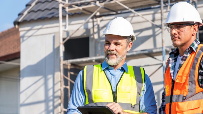 Energieeffizienz-Experten mit Sicherheitshelm und Warnwesten stehen auf einer Baustelle