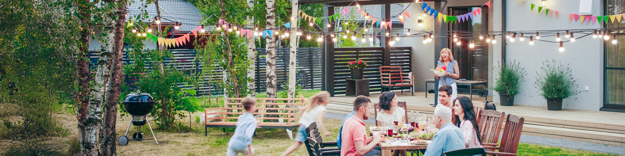 Familie mit Kindern feiern im Garten und sitzen am Tisch