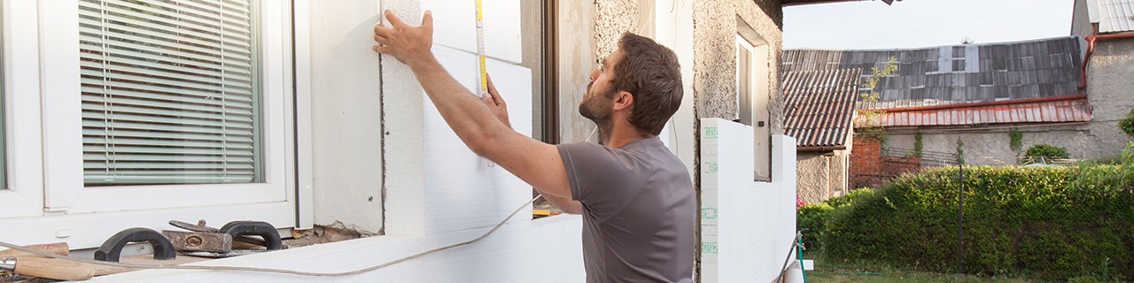 Ein Handwerker dämmt eine Fassade von außen