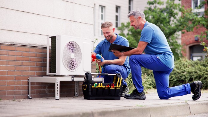 Handwerker, die eine Wärmepumpe an der Fassade eines Hauses anschließen