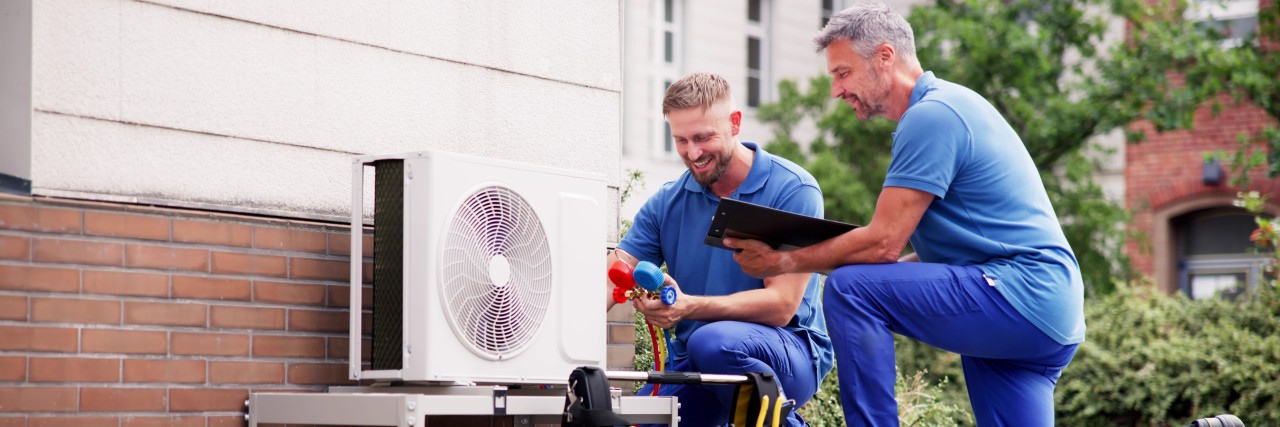 Handwerker, die eine Wärmepumpe an der Fassade eines Hauses anschließen