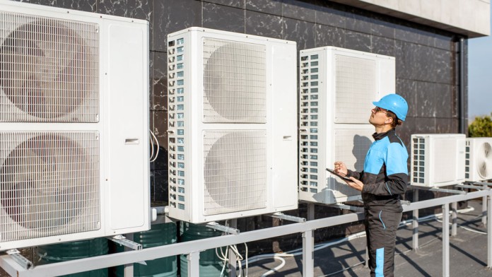 Handwerker, die eine Wärmepumpe an der Fassade eines Hauses anschließen