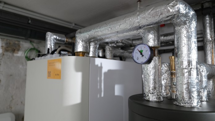 Nahaufnahme Heizsystem mit Rohrleitungen im Keller eines Gebäudes mit Luftdruckanzeige.