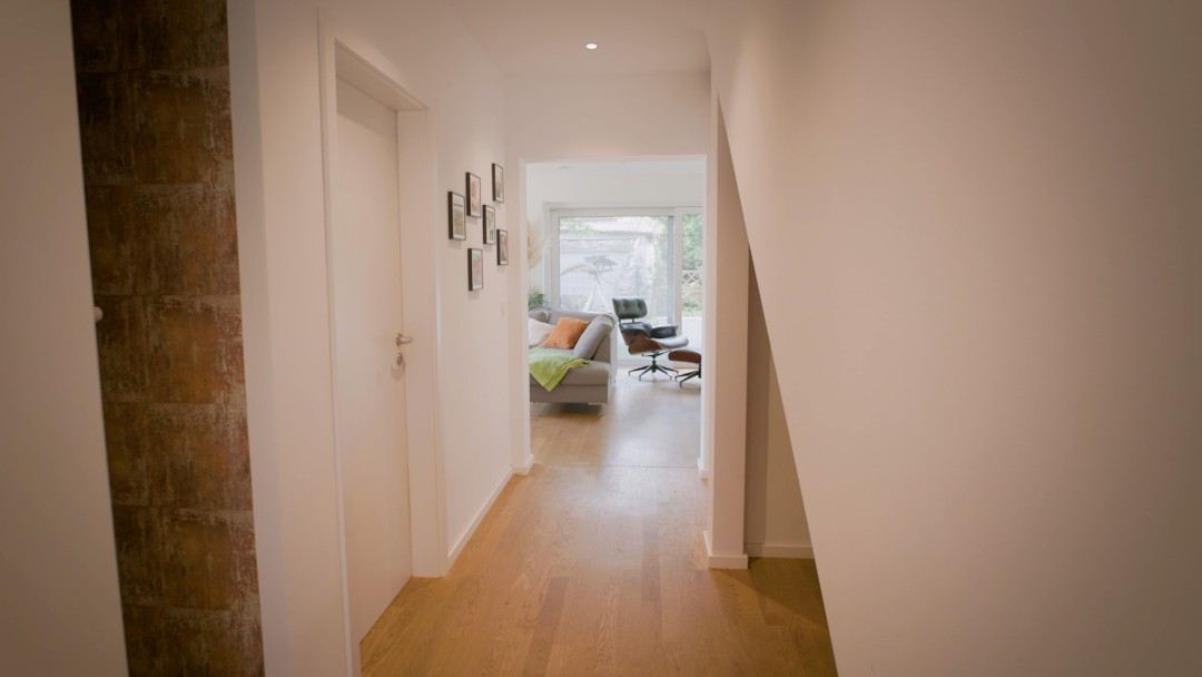 Blick in einen Fur, der in ein Wohnzimmer mündet und ein abgehendes Zimmer sowie eine Treppe nach oben aufweist