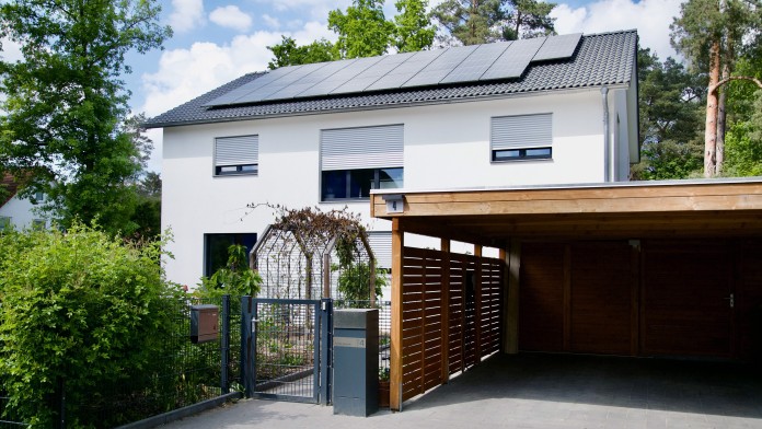 Außenansicht eines Einfamilienhaus mit Photovoltaikanlage auf dem Dach.