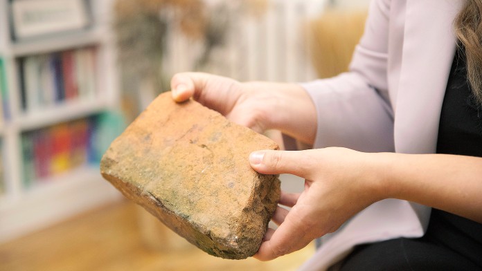 Eine Hand zeigt einen Stein, der beim Hausbau verwendet werden kann