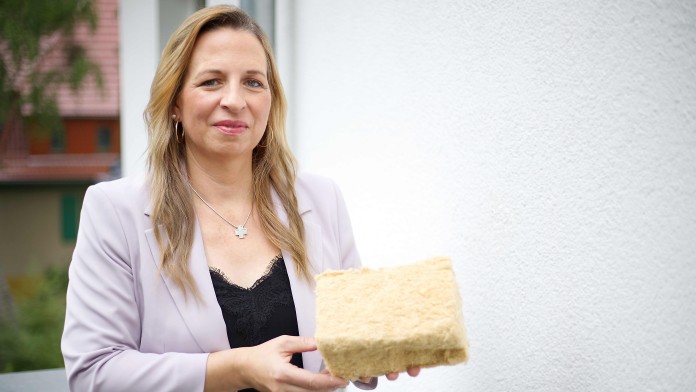 Eine Frau steht in einem haus und präsentiert Dämmmaterial